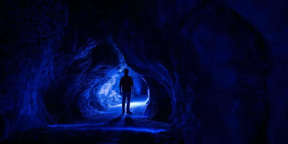 Wide cave passage in Ruakuri with limestone formations and guided tour group