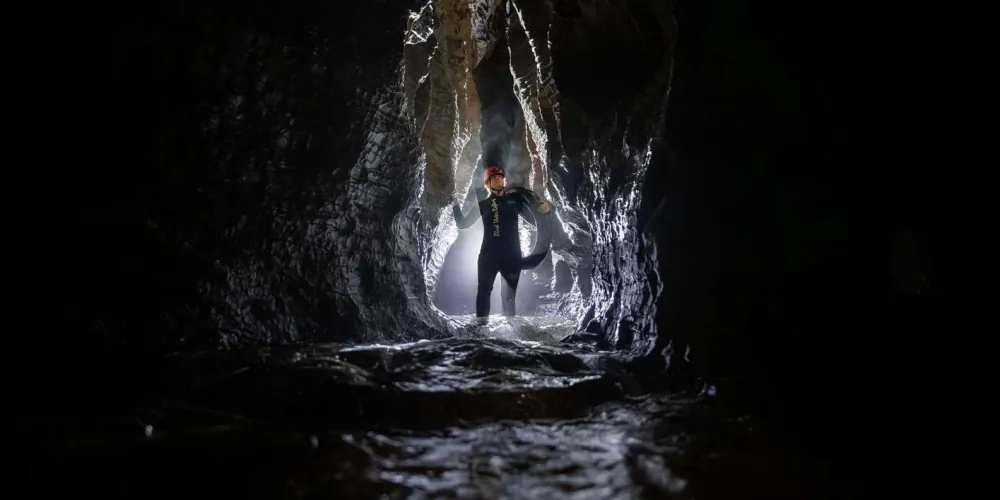 Wetsuit-clad adventurers floating on inner tubes through an underground cave passage