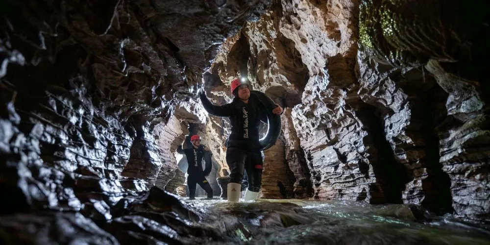 Adventurer preparing to leap off an underground waterfall in the Waitomo cave