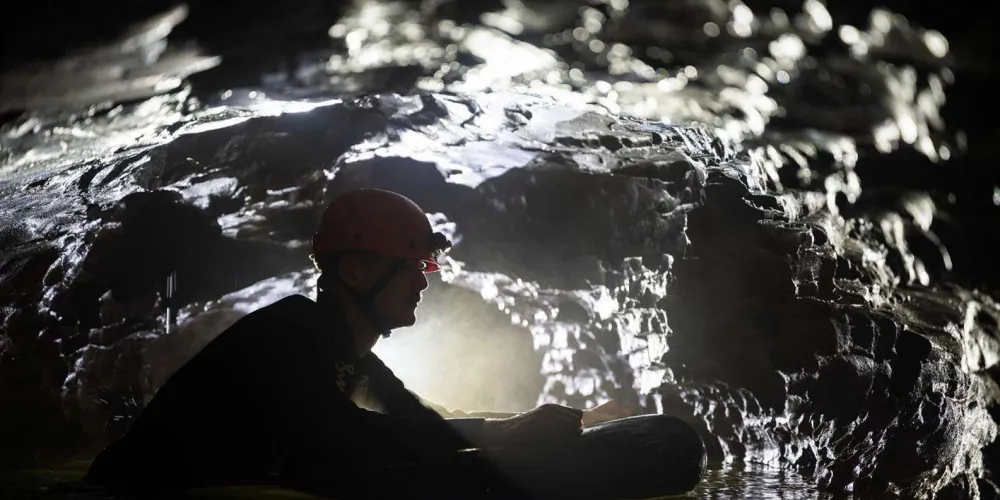 Group rafting through the Black Labyrinth underground river lit by headlamps