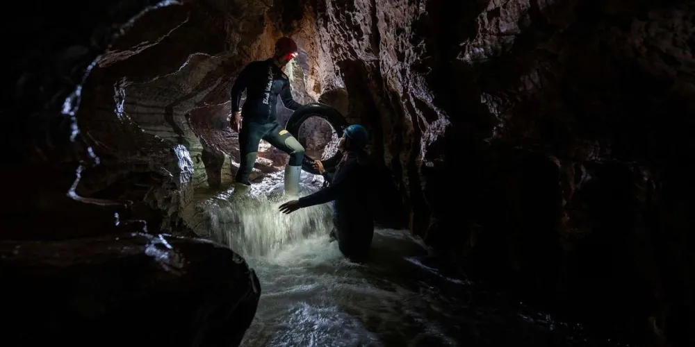 Adventurer abseiling 35 metres down into the Waitomo Black Abyss cave shaft