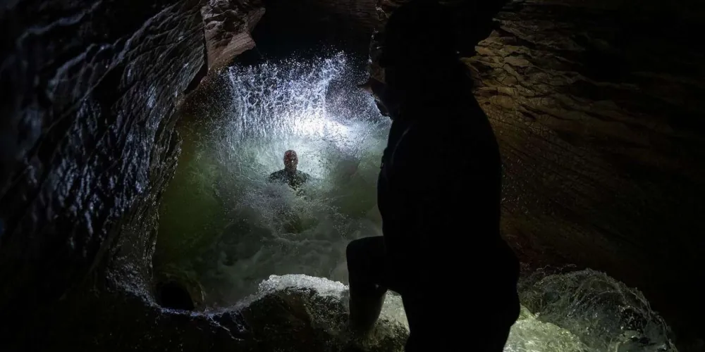 Participants on inner tubes in the Black Abyss cave system, helmets and wetsuits