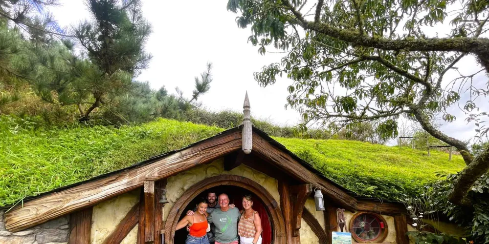 Visitors posing in the round doorway of a hobbit hole during a guided Hobbiton Movie Set tour